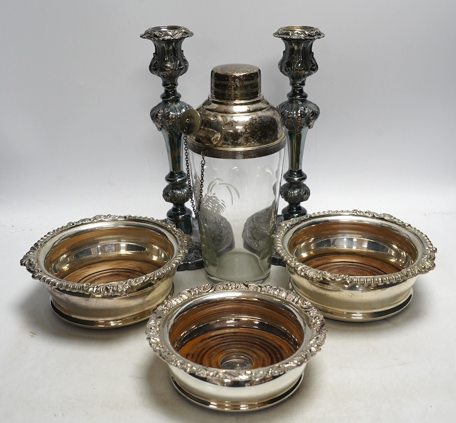 A pair of silver plated candlesticks, a pair and another wine coaster, and a cocktail shaker, tallest 25cm. Condition - fair